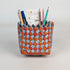 Pencil holder made from recycled cigarette packs with pens and paper on a white background