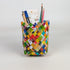 Colorful woven pencil holder with stationery items on a white background