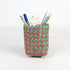 Woven pencil holder with stationery items on a white background