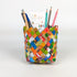 Colorful woven pencil holder with stationery items on a white background